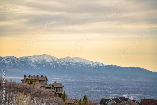 Hill homes with distant snow capped mountain toweing over lake and valley