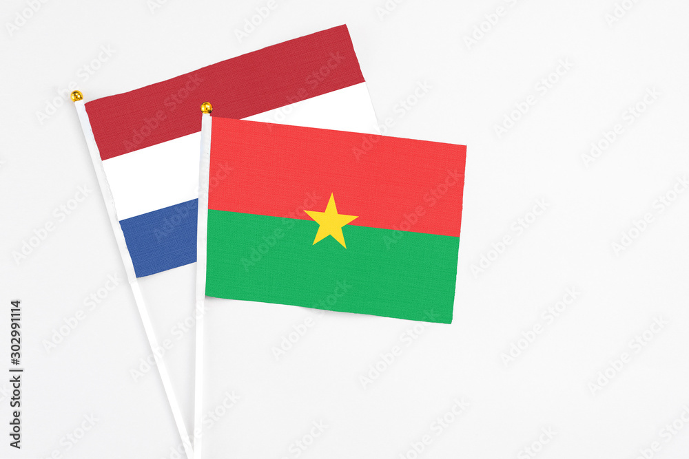 Burkina Faso and Netherlands stick flags on white background. High quality fabric, miniature national flag. Peaceful global concept.White floor for copy space. Burkina Faso and Netherlands stick flags on white background. High quality fabric, miniature national flag. Peaceful global concept.White floor for copy space.