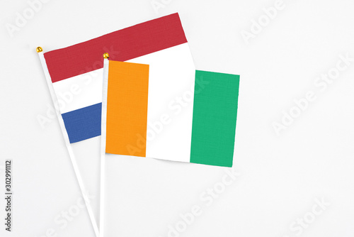 Free Download Cote D'Ivoire and Netherlands stick flags on white background. High quality fabric, miniature national flag. Peaceful global concept.White floor for copy space. - GFXLoad