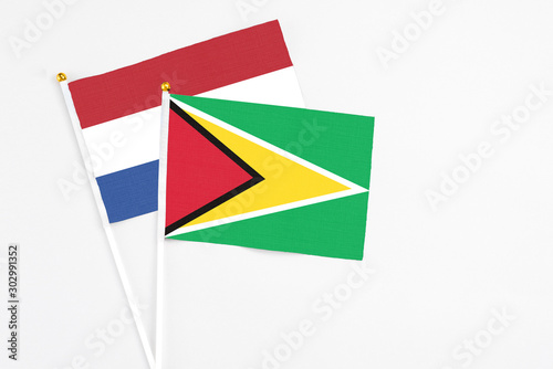 Free Download Guyana and Netherlands stick flags on white background. High quality fabric, miniature national flag. Peaceful global concept.White floor for copy space. - GFXLoad