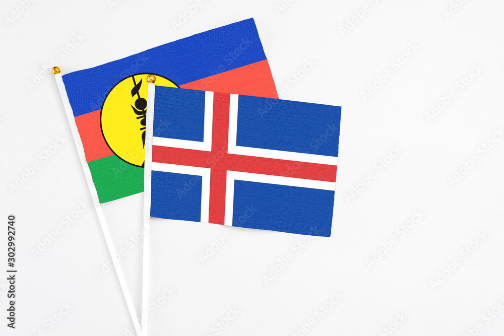 Iceland and New Caledonia stick flags on white background. High quality fabric, miniature national flag. Peaceful global concept.White floor for copy space.