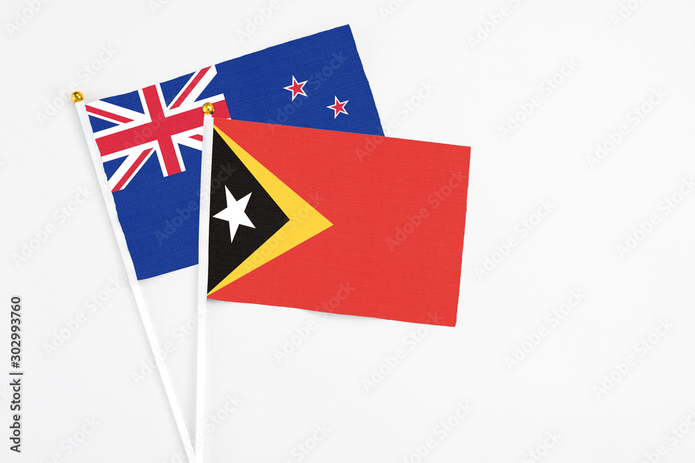 East Timor and New Zealand stick flags on white background. High quality fabric, miniature national flag. Peaceful global concept.White floor for copy space. East Timor and New Zealand stick flags on white background. High quality fabric, miniature national flag. Peaceful global concept.White floor for copy space.