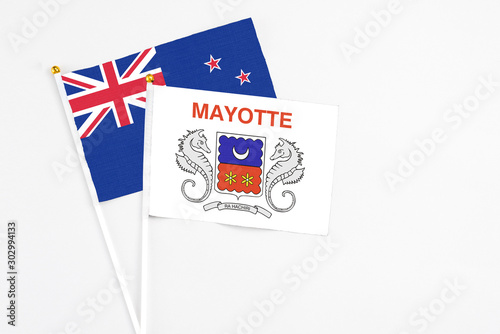 Mayotte and New Zealand stick flags on white background. High quality fabric, miniature national flag. Peaceful global concept.White floor for copy space.