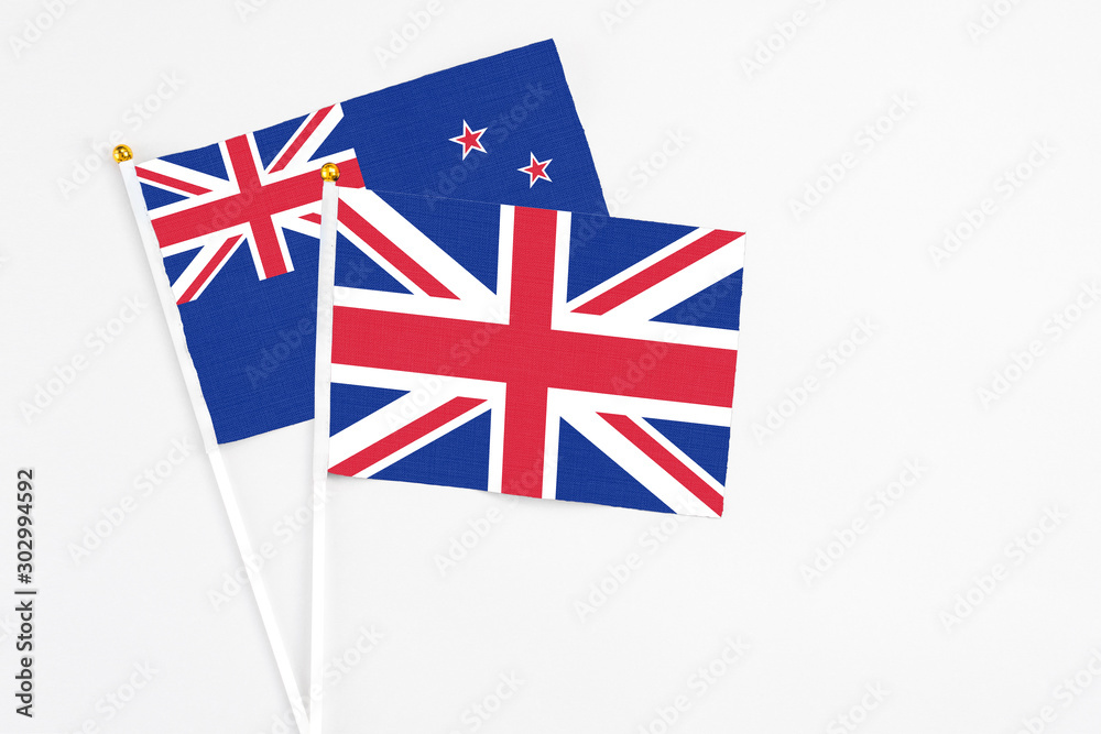 United Kingdom and New Zealand stick flags on white background. High quality fabric, miniature national flag. Peaceful global concept.White floor for copy space. United Kingdom and New Zealand stick flags on white background. High quality fabric, miniature national flag. Peaceful global concept.White floor for copy space.