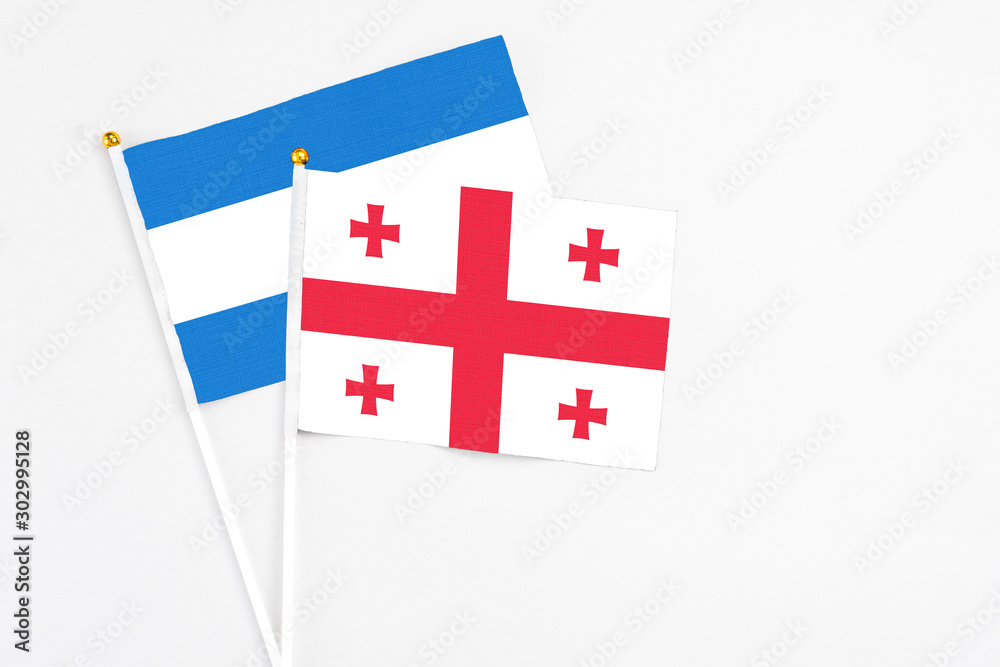 Georgia and Nicaragua stick flags on white background. High quality fabric, miniature national flag. Peaceful global concept.White floor for copy space.