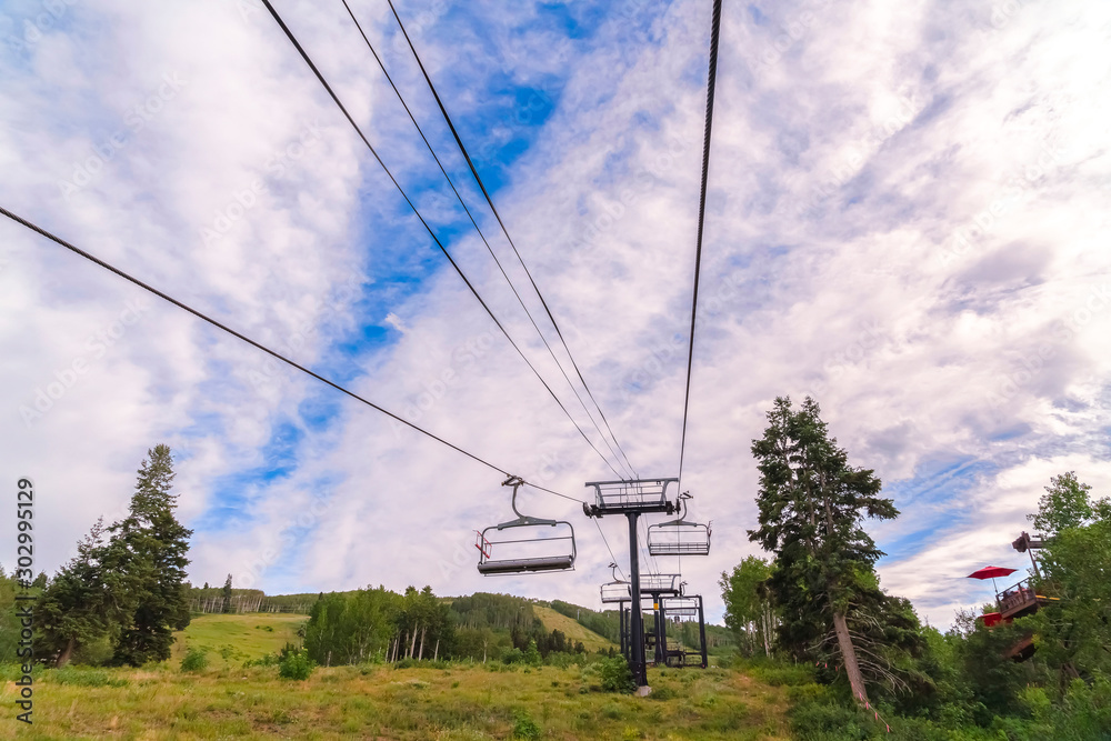 View of chairlifts against cloud covered blue sky during off season in Park City