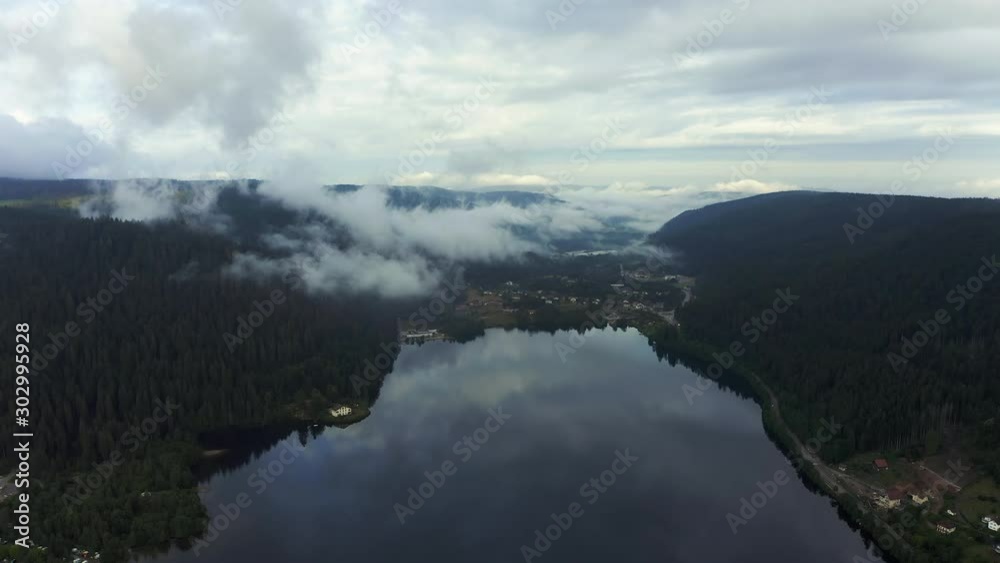 Panning aerial shot of a lake reflecting the low hanging clouds on a partly cloudy morning. Panning aerial shot of a lake reflecting the low hanging clouds on a partly cloudy morning.