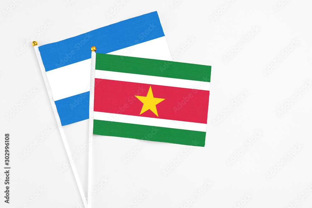 Fototapeta premium Suriname and Nicaragua stick flags on white background. High quality fabric, miniature national flag. Peaceful global concept.White floor for copy space.