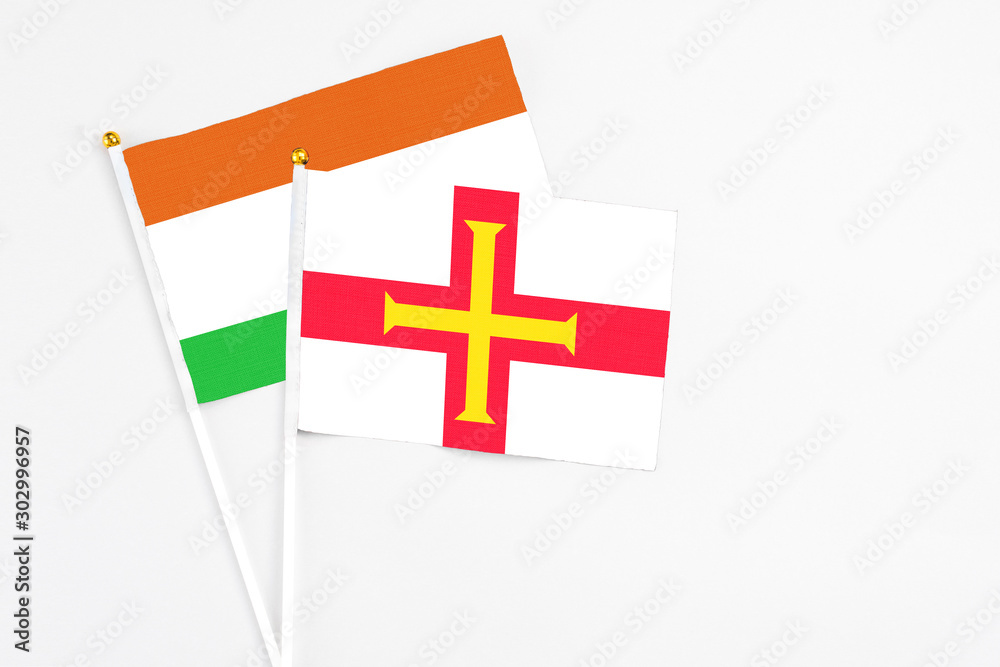 Guernsey and Niger stick flags on white background. High quality fabric, miniature national flag. Peaceful global concept.White floor for copy space.