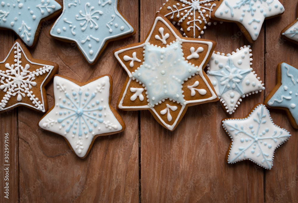 Homemade gingersnaps covered with icing on the wooden background; delicious cookies with Christmas shapes