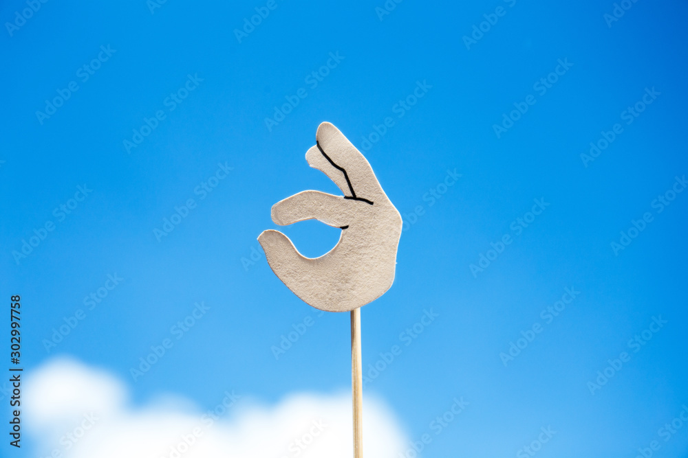 paper cut okay sign on blue sky background