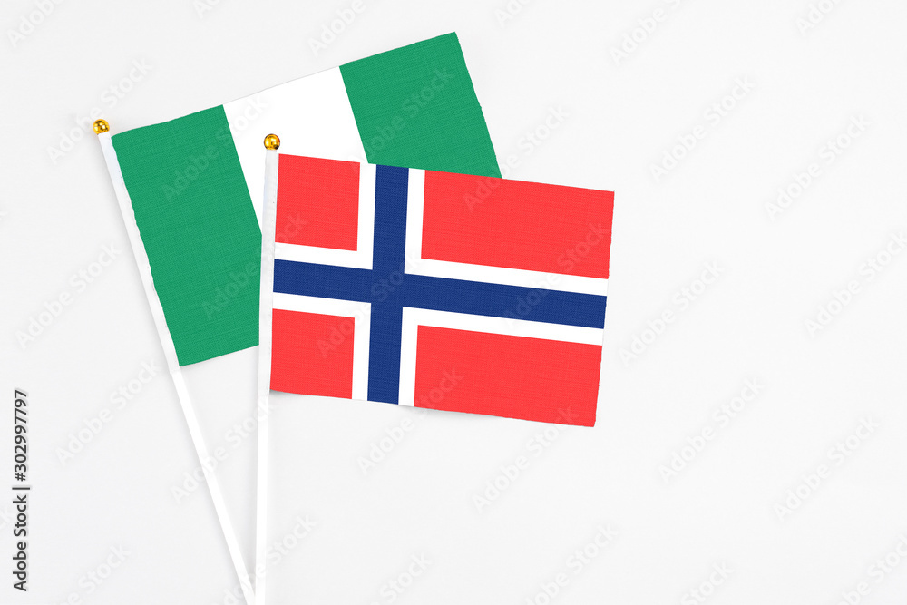 Bouvet Islands and Nigeria stick flags on white background. High quality fabric, miniature national flag. Peaceful global concept.White floor for copy space.