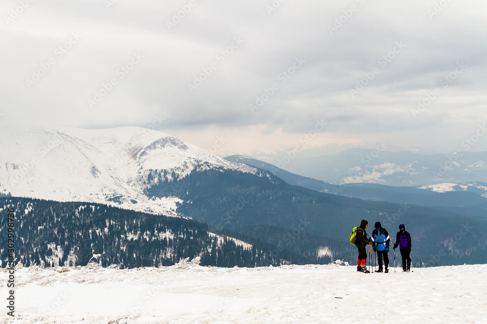 high in the mountains is a group of three people, in the background is Hoverla Mountain, Carpathians, Ukraine.