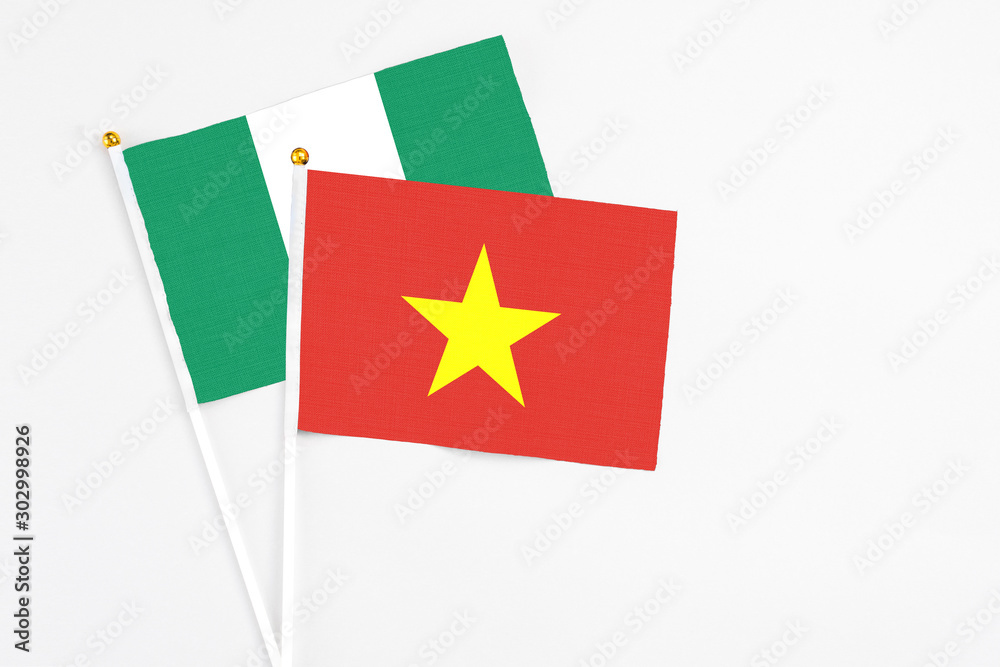 Vietnam and Nigeria stick flags on white background. High quality fabric, miniature national flag. Peaceful global concept.White floor for copy space. Vietnam and Nigeria stick flags on white background. High quality fabric, miniature national flag. Peaceful global concept.White floor for copy space.