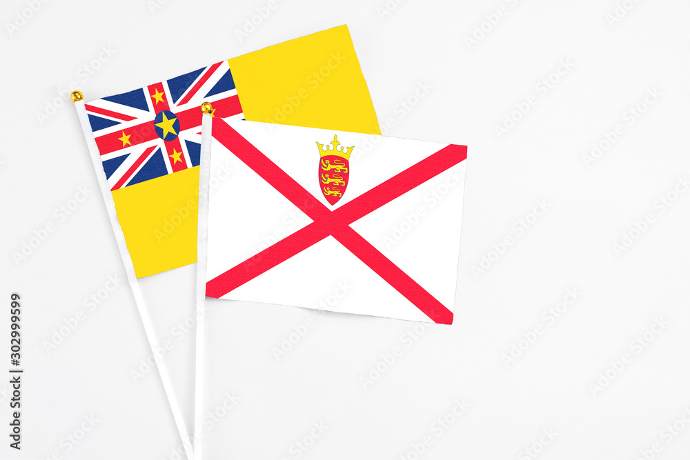 Jersey and Niue stick flags on white background. High quality fabric, miniature national flag. Peaceful global concept.White floor for copy space. Jersey and Niue stick flags on white background. High quality fabric, miniature national flag. Peaceful global concept.White floor for copy space.