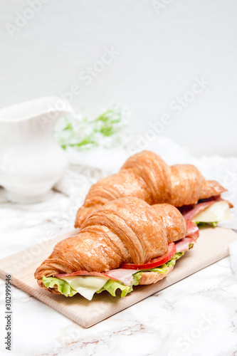 Sandwich croissant on a marble surface and wooden plate 