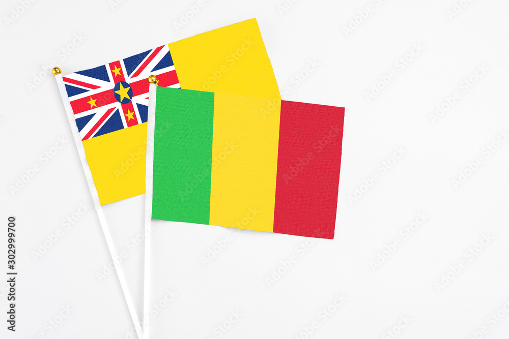 Mali and Niue stick flags on white background. High quality fabric, miniature national flag. Peaceful global concept.White floor for copy space.