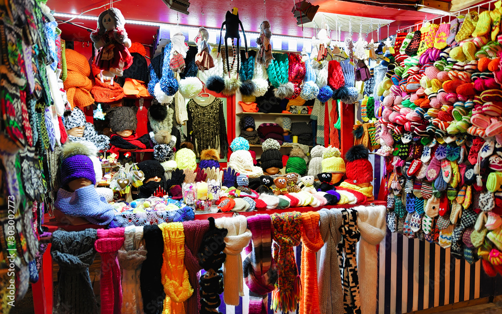 Wool mittens, gloves, socks with hats on stalls at Christmas market in Riga of Latvia winter. Street Xmas and holiday fair in European city or town. Advent Decoration with Crafts Items on Bazaar