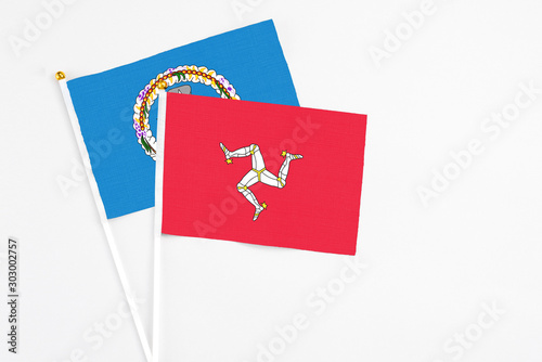 Isle Of Man and Northern Mariana Islands stick flags on white background. High quality fabric, miniature national flag. Peaceful global concept.White floor for copy space.