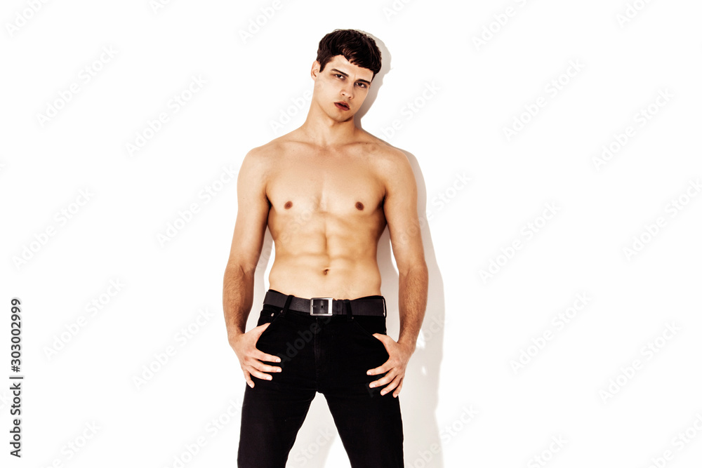 Muscle strong beautiful stripped male model in denim jeans on white isolated font background with shadow Muscle strong beautiful stripped male model in denim jeans on white isolated font background with shadow