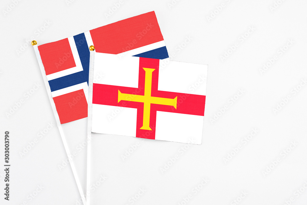 Guernsey and Norway stick flags on white background. High quality fabric, miniature national flag. Peaceful global concept.White floor for copy space.