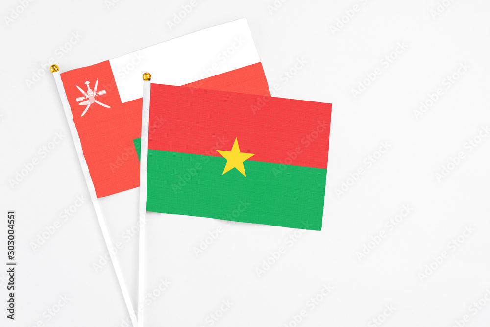 Burkina Faso and Oman stick flags on white background. High quality fabric, miniature national flag. Peaceful global concept.White floor for copy space. Burkina Faso and Oman stick flags on white background. High quality fabric, miniature national flag. Peaceful global concept.White floor for copy space.