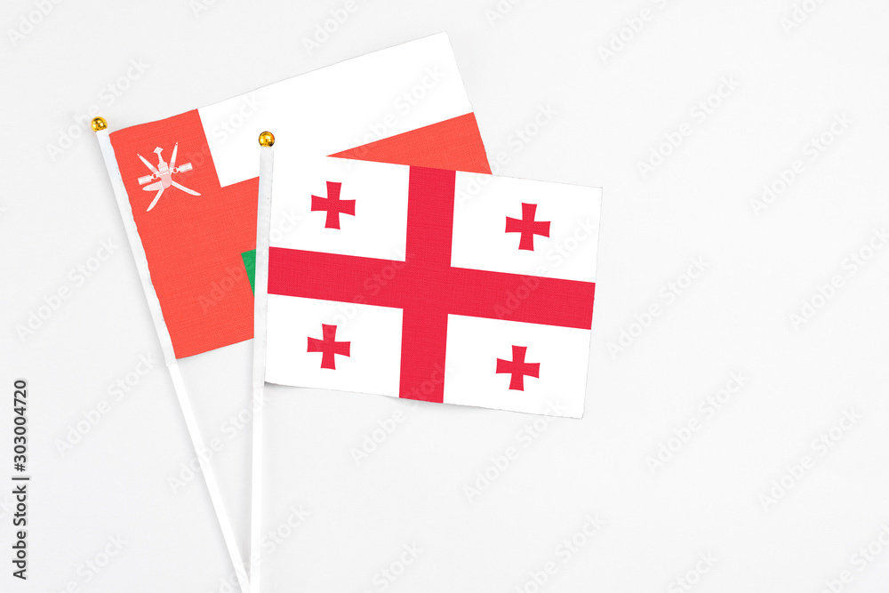 Georgia and Oman stick flags on white background. High quality fabric, miniature national flag. Peaceful global concept.White floor for copy space.