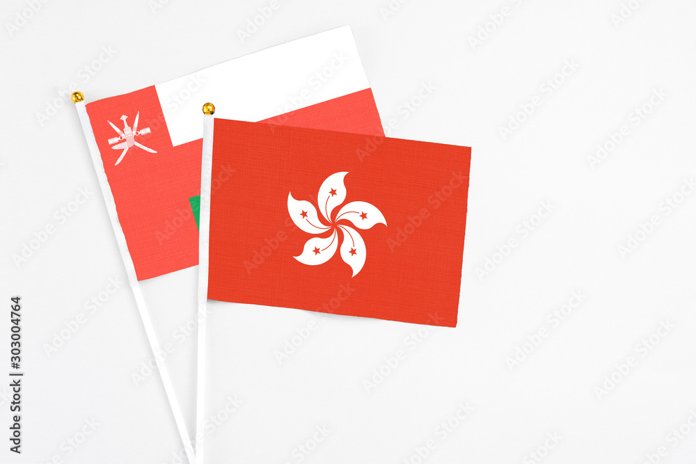 Hong Kong and Oman stick flags on white background. High quality fabric, miniature national flag. Peaceful global concept.White floor for copy space.