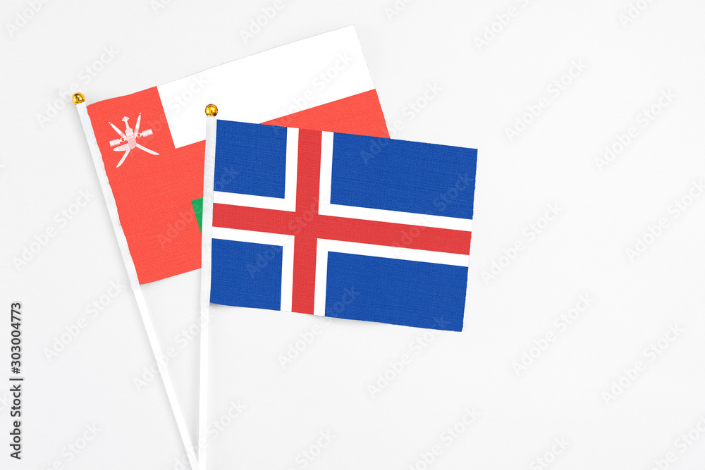 Iceland and Oman stick flags on white background. High quality fabric, miniature national flag. Peaceful global concept.White floor for copy space.