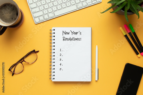 Stock photo of 2020 new year notebook with list of resolutions and objects on yellow background