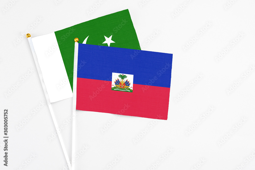 Haiti and Pakistan stick flags on white background. High quality fabric, miniature national flag. Peaceful global concept.White floor for copy space.