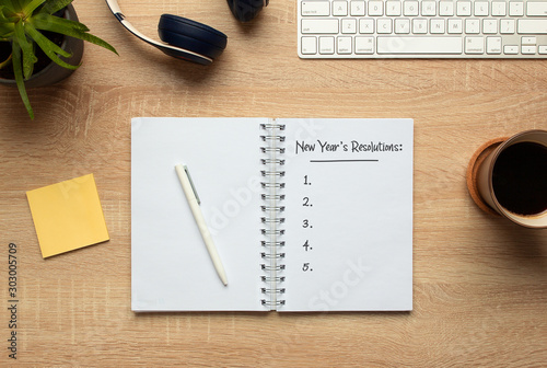 Stock photo of new year notebook with list of resolutions and objects on wooden background photo