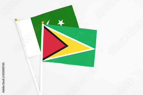 Guyana and Pakistan stick flags on white background. High quality fabric  miniature national flag. Peaceful global concept.White floor for copy space.
