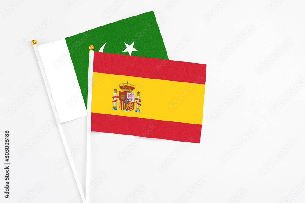 Obraz premium Spain and Pakistan stick flags on white background. High quality fabric, miniature national flag. Peaceful global concept.White floor for copy space.
