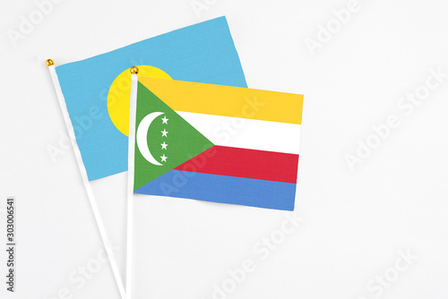 Comoros and Palau stick flags on white background. High quality fabric, miniature national flag. Peaceful global concept.White floor for copy space. photo