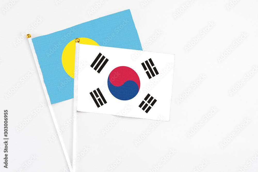 South Korea and Palau stick flags on white background. High quality fabric, miniature national flag. Peaceful global concept.White floor for copy space.