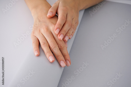 Women's hands with a nice manicure on white-gray background.