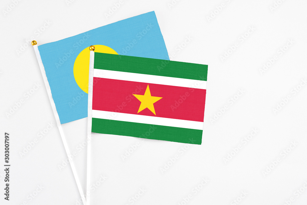 Naklejka premium Suriname and Palau stick flags on white background. High quality fabric, miniature national flag. Peaceful global concept.White floor for copy space.
