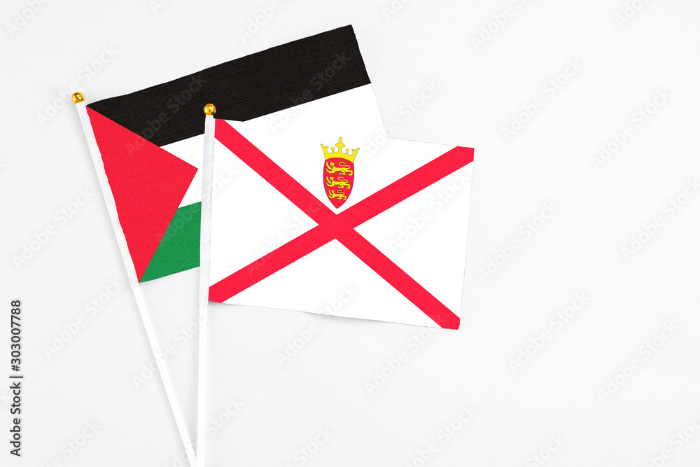 Jersey and Palestine stick flags on white background. High quality fabric, miniature national flag. Peaceful global concept.White floor for copy space.