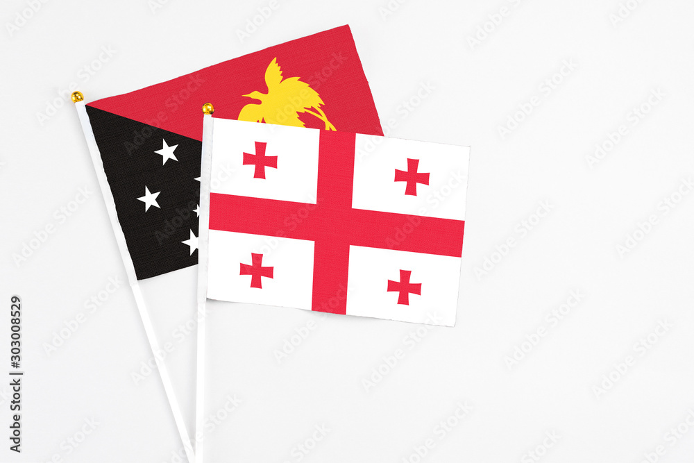 Georgia and Papua New Guinea stick flags on white background. High quality fabric, miniature national flag. Peaceful global concept.White floor for copy space.