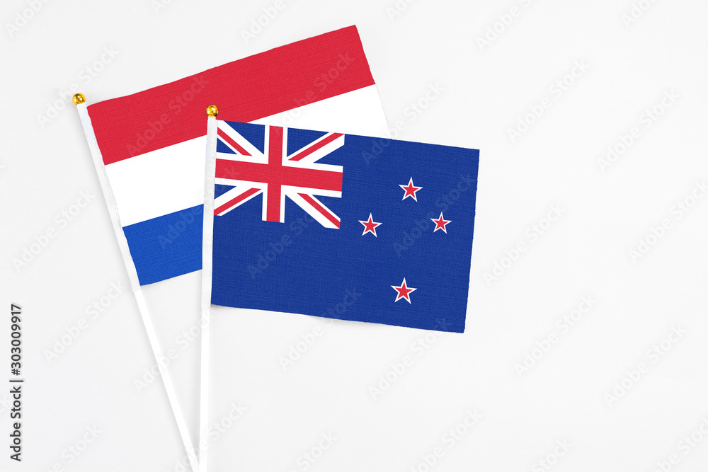 Fototapeta premium New Zealand and Paraguay stick flags on white background. High quality fabric, miniature national flag. Peaceful global concept.White floor for copy space.