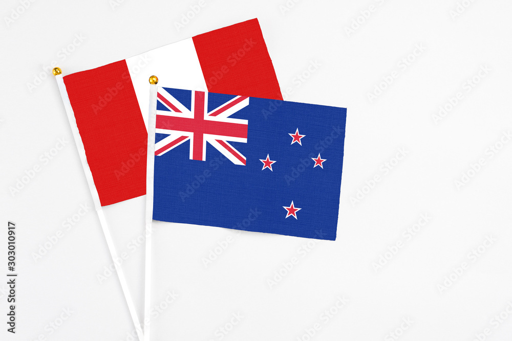 New Zealand and Peru stick flags on white background. High quality fabric, miniature national flag. Peaceful global concept.White floor for copy space.