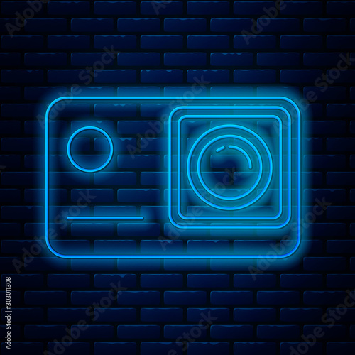 Glowing neon line Action extreme camera icon isolated on brick wall background. Video camera equipment for filming extreme sports. Vector Illustration