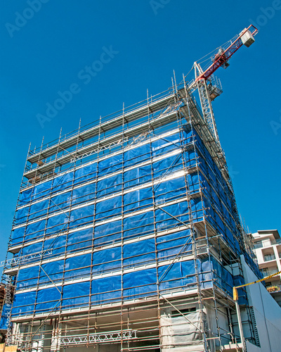 A working Construction crane on top of a highrise building with a blue sky background. Australia. photo