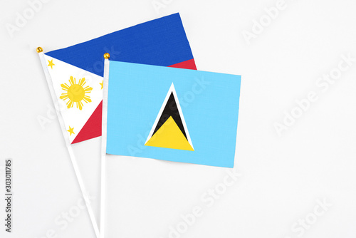 Saint Lucia and Philippines stick flags on white background. High quality fabric, miniature national flag. Peaceful global concept.White floor for copy space.