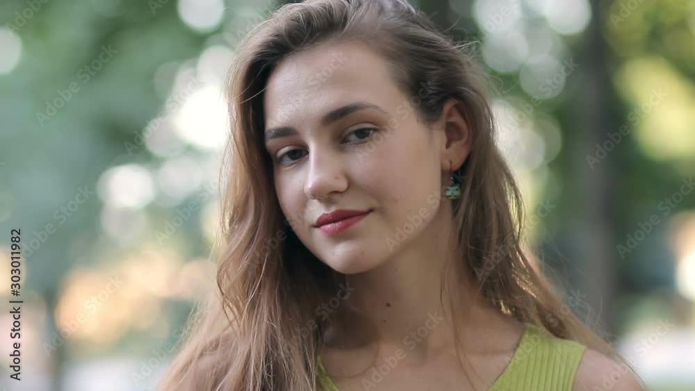 Portrait of beautiful young woman student smiling at camera looking confident pretty standing in park on summer day Portrait of beautiful young woman student smiling at camera looking confident pretty standing in park on summer day