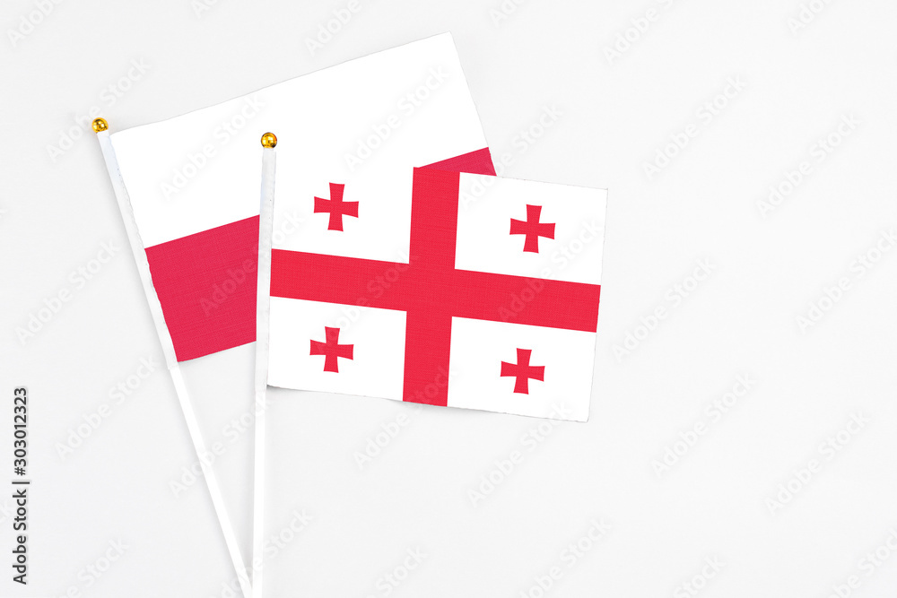 Georgia and Poland stick flags on white background. High quality fabric, miniature national flag. Peaceful global concept.White floor for copy space.