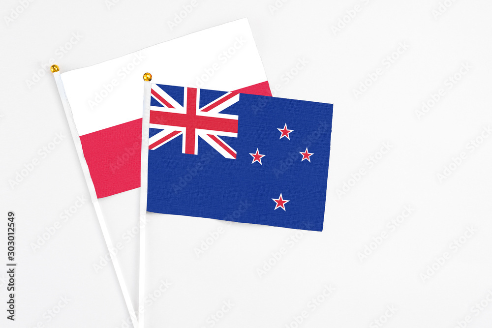 New Zealand and Poland stick flags on white background. High quality fabric, miniature national flag. Peaceful global concept.White floor for copy space.