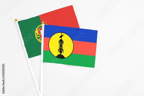 Free Download New Caledonia and Portugal stick flags on white background. High quality fabric, miniature national flag. Peaceful global concept.White floor for copy space. - GFXLoad