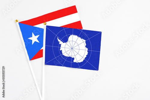 Antarctica and Puerto Rico stick flags on white background. High quality fabric, miniature national flag. Peaceful global concept.White floor for copy space.